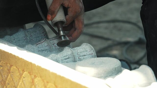 Craftsman chiseling stone by hand in traditional sculpture workshop India stonework craftsmanship