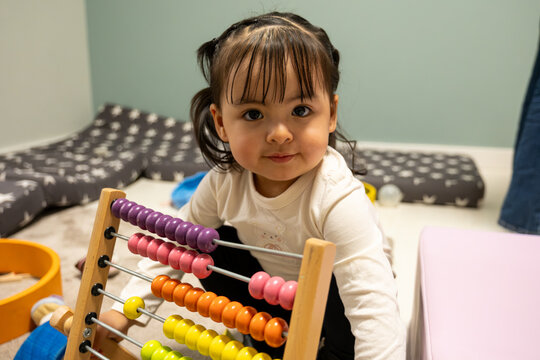 Toddler girl learning counting skills with an abacus in a bright nursery