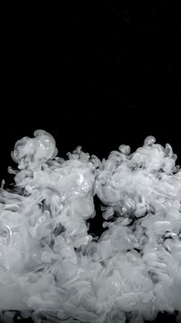 White Ink Swirling and Dissolving in Water Against a Black Background