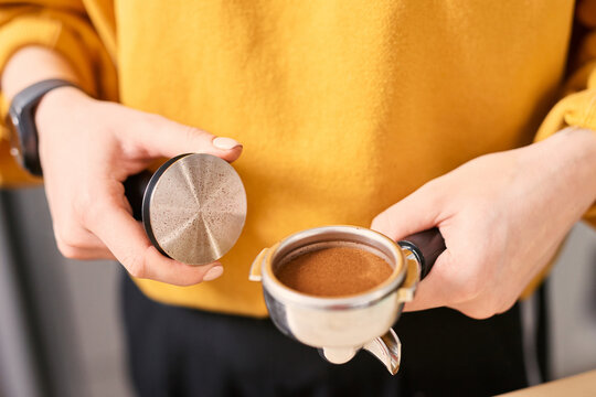 Barista holding a temper and portafilter filled with coffee