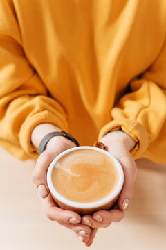 Offering a fresh coffee latte in a cup in hands