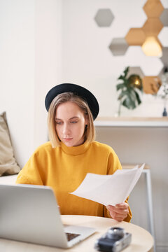 Woman working with papers and on a laptop, typing on keyboard, close up