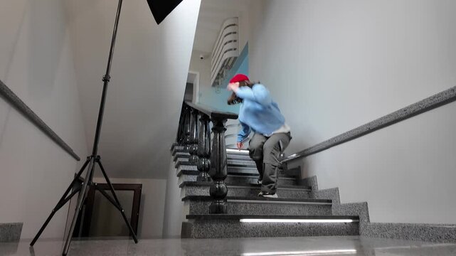 Young Woman in Red Beanie Freestyle Dancing Hip Hop on a Staircase in a Modern Building Lobby