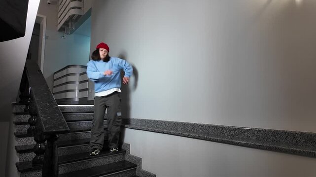 Young Woman in Red Beanie Freestyle Dancing Hip Hop on a Staircase in a Modern Building Lobby