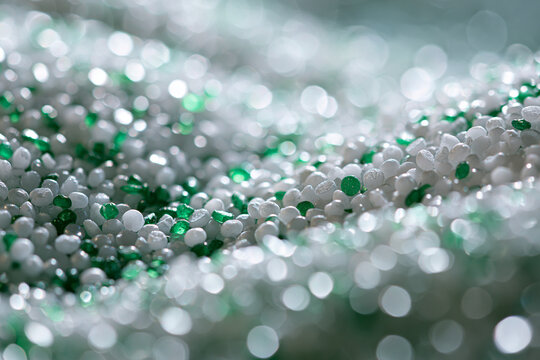 Abstract macro background of white and green plastic granules, specifically polypropylene (PP) and acrylonitrile styrene acrylate (ASA) polymers, highlighting raw industrial materials,