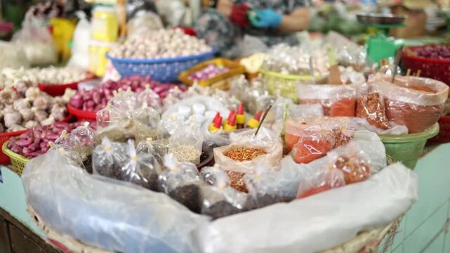 Close-up of various spices, seasonings, and aromatics in plastic bags and bowls displayed on a stall at Xom Moi Market in Nha Trang, Vietnam. Commercial food supply and retail trade concept.