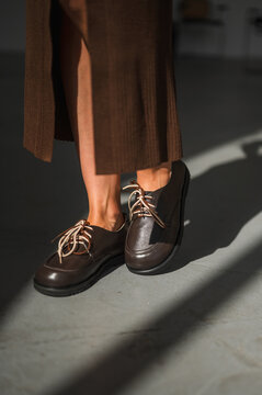 Closeup of legs in brown midi skirt with leather laceup shoes and sunlight shadow, with skirt, brown, midi, ribbed detail, showing slit, leg, legs, ankle context