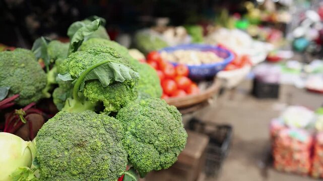 Close-up of fresh green broccoli heads and vegetables displayed on a stall at Xom Moi Market in Nha Trang, Vietnam. Commercial food supply, local greengrocer and retail trade concept.