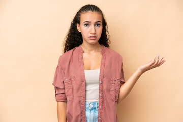 Obraz premium Young woman isolated on beige background making doubts gesture