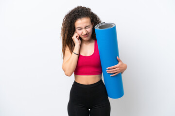 Young sport Arab woman going to yoga classes while holding a mat isolated on white background frustrated and covering ears © luismolinero
