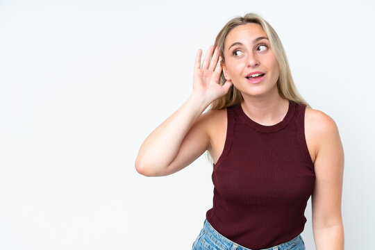 Young caucasian woman isolated on white background listening to something by putting hand on the ear