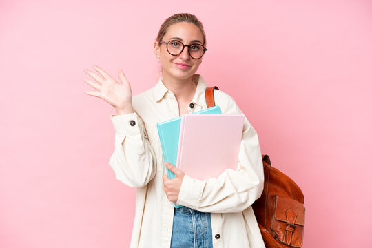 Young student caucasian woman isolated on pink background saluting with hand with happy expression