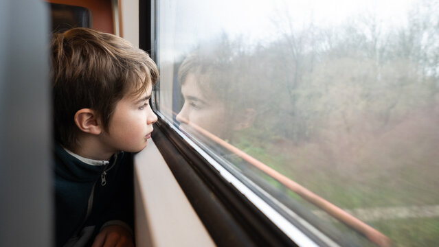 Boy traveling by train looking out through window