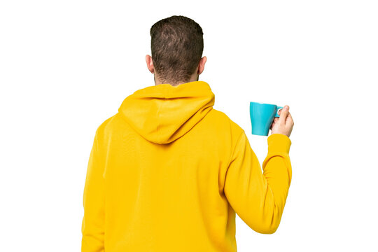 Young handsome blonde man holding cup of coffee over isolated background in back position