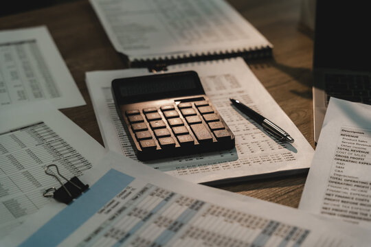 Calculator on financial reports with pen and documents for bookkeeping, accounting review, audit, budget checking and financial planning in office.