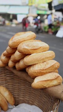 Close-up of fresh crispy Vietnamese baguettes or banh mi stacked in wicker baskets for sale at Xom Moi Market in Nha Trang, Vietnam. Local bakery, street food supply and retail trade concept.