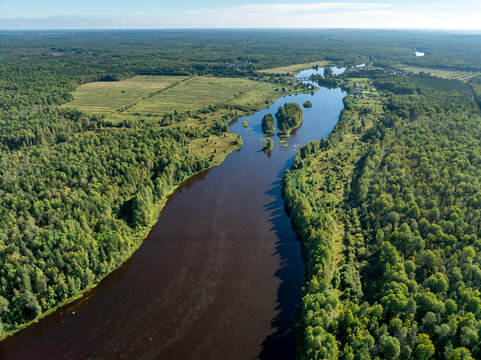 Aerial view of a winding river meandering through green taiga forest and fields near Kindasovo village in Karelia, Russi