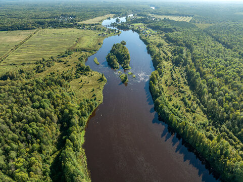 Aerial view of a winding river meandering through green taiga forest and fields near Kindasovo village in Karelia, Russia