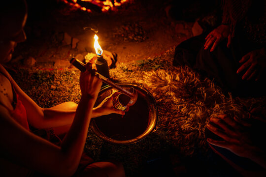 Serving ceremonial cacao during a sacred spiritual fire ceremony at night
