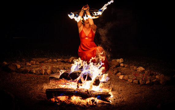 Woman Performing a Mystical Fire Ritual with Flaming Fan at Night.