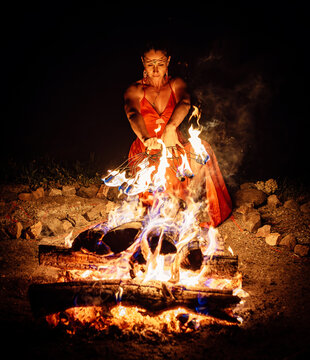 Woman Performing a Mystical Fire Ritual with Flaming Fan at Night.