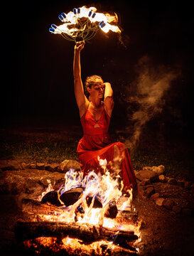 Woman Performing a Mystical Fire Ritual with Flaming Fan at Night.