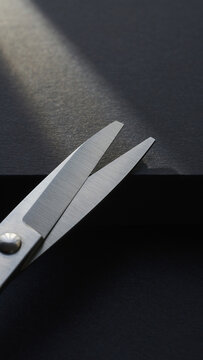 Close-up of Open Scissors Above Dark Cardboard