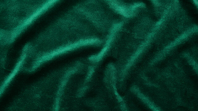 Dark green velvet fabric texture. Luxury emerald textile background with soft folds.