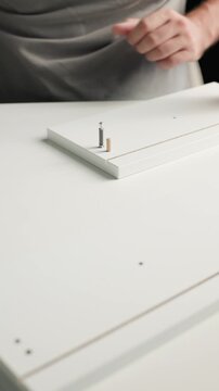 Close up of a man assembling furniture parts together indoors, connecting components during a regular speed DIY home project