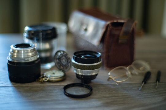 vintage retro camera photo lenses, old fashioned and retro pocket watch with lid on wooden table