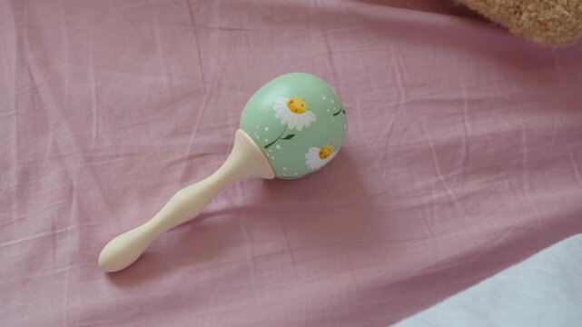 Close-up isolates baby rattle beside quiet family activity. Shape, texture, and small details become visual focus, offering clean subject for childhood, sensory play, and early development themes.
