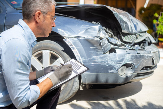 Insurance adjuster assessing damage to a car after a traffic accident.