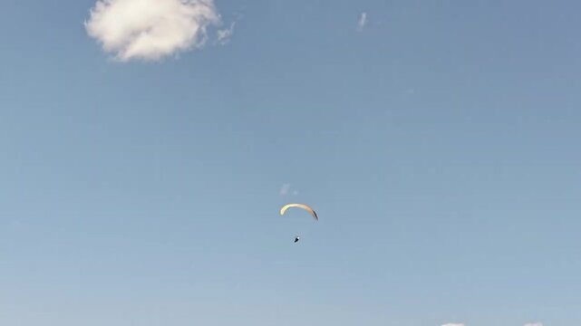 Spectacular drone tracking shot of an extreme paraglider gliding high in the sky