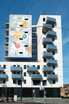 Vienna, Austria - August 24, 2025: Modern residential building facade with large mural artwork and blue balconies. 