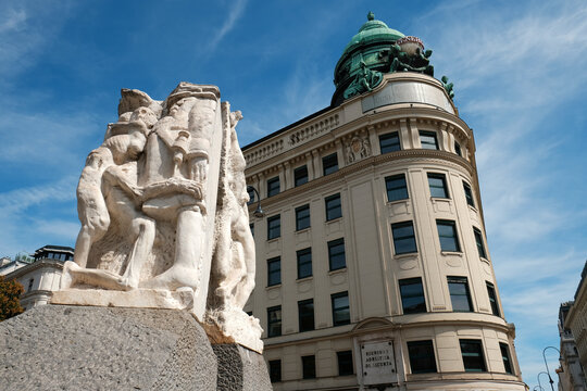 Vienna, Austria - August 18, 2025. Low angle view featuring the Monument Against War and Fascism sculptures in the foreground with the historic Generali building in the background.