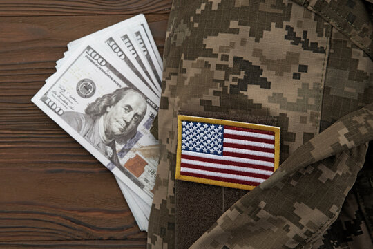 US Army uniform with American flag patch and one hundred dollar banknotes. Military funding, defense spending and government budget, soldier salary
