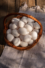 Chicken eggs in a wicker large basket on wooden grunge table. Countryside outdoor setting © TSViPhoto