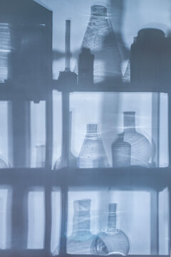 Abstract background with shadows of laboratory equipment and glassware projected on a surface, blue cinematic lighting, science backdrop with copy space.