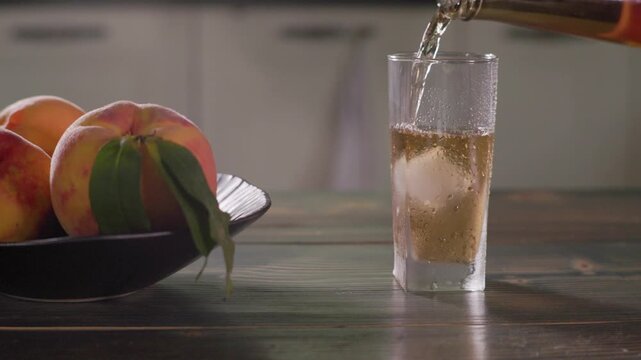 Pouring Peach Drink Into Glass With Ice Cubes Close Up Slow Motion
