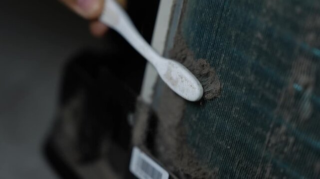 Cleaning dust from appliance filter with toothbrush, Close-up of a person cleaning thick dust from an appliance vent or filter with a toothbrush