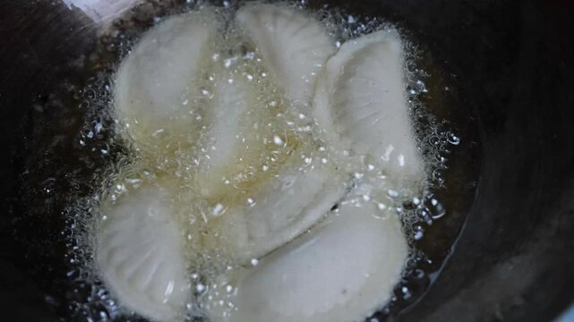 Dumplings frying in hot oil with bubbles in a close-up kitchen scene