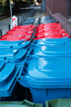 Row of different-colored trash cans for recycling next to an office building in Frankfurt am Main Germany. Waste management, garbage bin, waste disposal, recyclables, garbage collection.