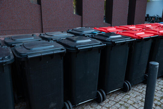 Row of different-colored trash cans for recycling next to an office building in Frankfurt am Main Germany. Waste management, garbage bin, waste disposal, recyclables, garbage collection.