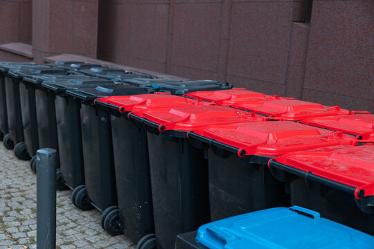 Row of different-colored trash cans for recycling next to an office building in Frankfurt am Main Germany. Waste management, garbage bin, waste disposal, recyclables, garbage collection.