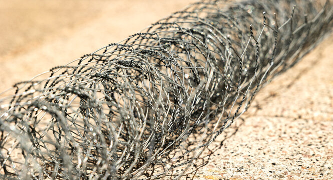 Close-up of a rolled up chain-link fence, metal wire or wire mesh. Fencing used to enclose a property or for an animal pen, such as in the raising of chickens, ducks, or goats.