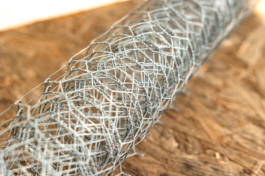 Close-up of a rolled up chain-link fence, metal wire or wire mesh. Fencing used to enclose a property or for an animal pen, such as in the raising of chickens, ducks, or goats.