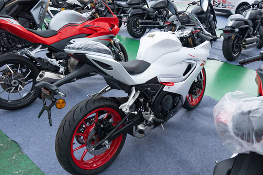 ZhongShan GuangDong China-April 11 2026: QJMOTOR white sport motorcycle with red wheel rims exhibited at outdoor motor show.