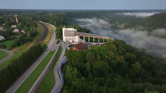 Aerial view of Sigulda bobsleigh and luge track surrounded by forest and morning fog in Latvia