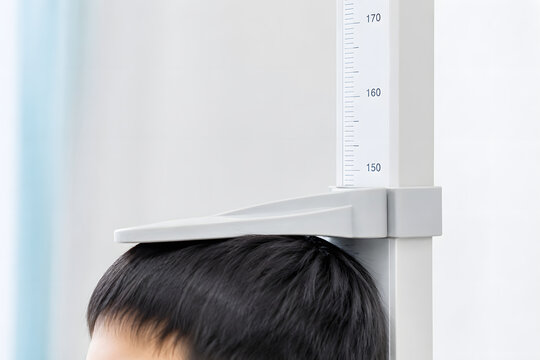 Close up of child head being measured for height with stadiometer scale in medical clinic or school health checkup.