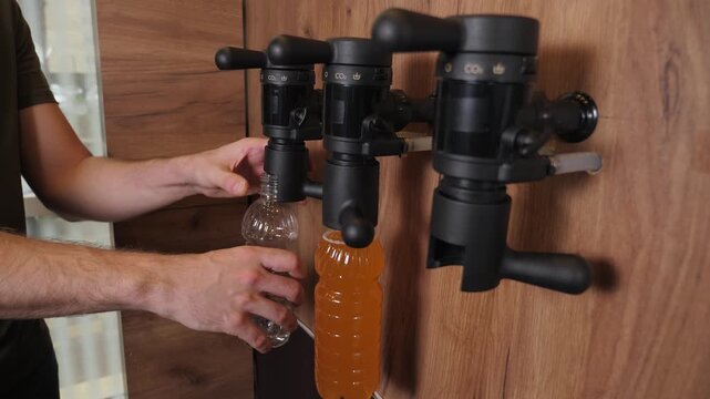 The bartender pours fresh craft beer into a plastic bottle at the bar. Draft light beer. A man bottles beer. An automated method for bottling fresh beer.